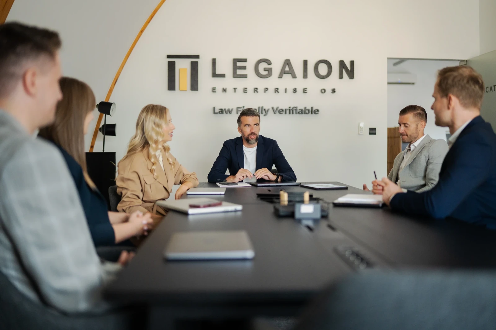 Cały zespół LEGAION przy stole konferencyjnym, logo LEGAION w tle